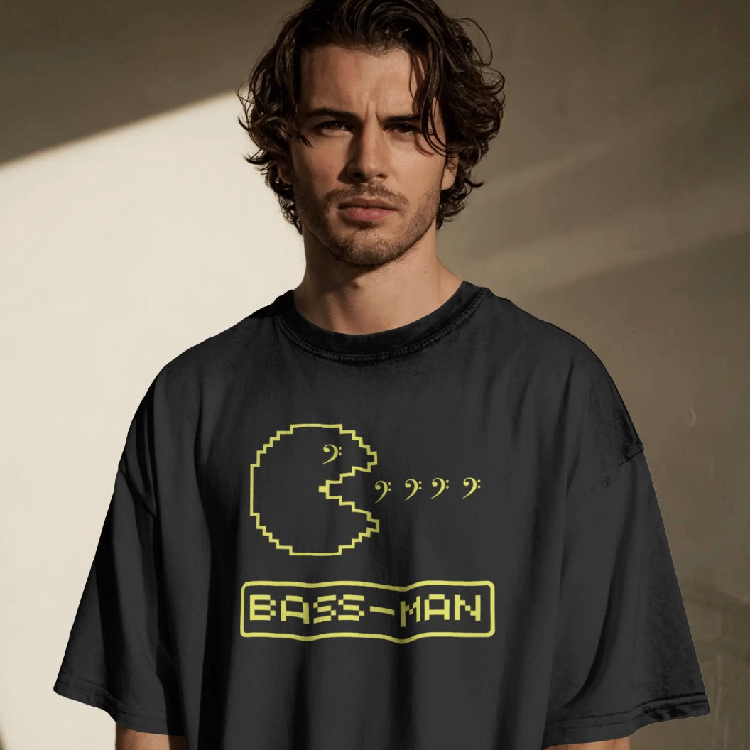 Man wearing a black t-shirt with a yellow graphic and Bass Man text against a neutral background