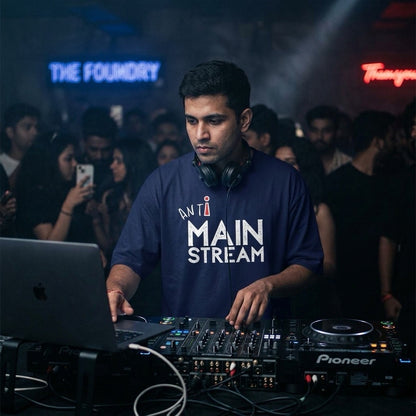 DJ operating equipment at a music event with 'Anti Mainstream' T-shirt