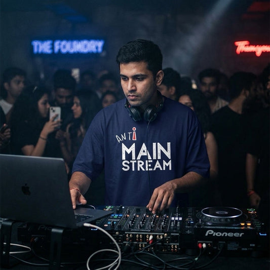 DJ operating equipment at a music event with 'Anti Mainstream' T-shirt