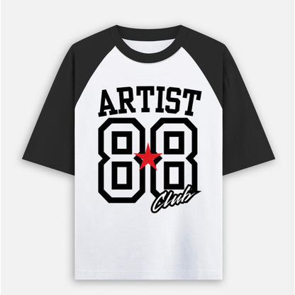 A raglan-style baseball t-shirt with a white body and black sleeves, featuring a graphic print on the front with the text 'ARTIST 88 Club' and a red star accent.