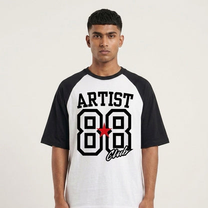 A man wearing a black and white raglan t-shirt with a graphic on the front that reads 'ARTIST 88 Club' in black and white with a small red star accent, set against a plain light background.