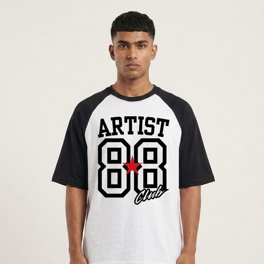 A man wearing a black and white raglan t-shirt with a graphic on the front that reads 'ARTIST 88 Club' in black and white with a small red star accent, set against a plain light background.