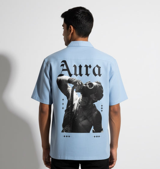 Person wearing a light blue shirt with 'Aura' design on the back