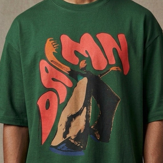Person wearing a green t-shirt with a colorful DAMN design on a textured brown background