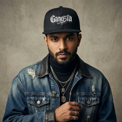 rapper wearing a denim jacket and 'Gangsta' cap against a neutral background