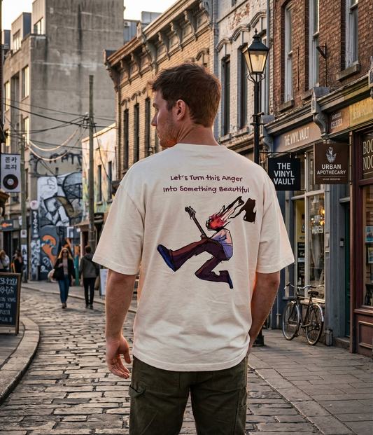 Man walking down a city street wearing a drummerkong t-shirt with a graphic design on the back.