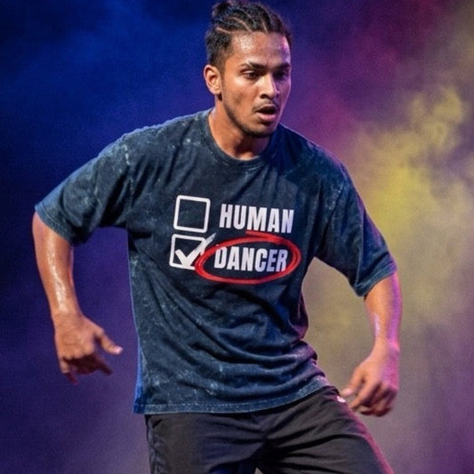 Dancer performing on stage wearing DrummerKong T-shirt with colorful lights and audience in the foreground