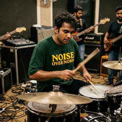 drummer playing drums in a music studio with other musicians and equipment.