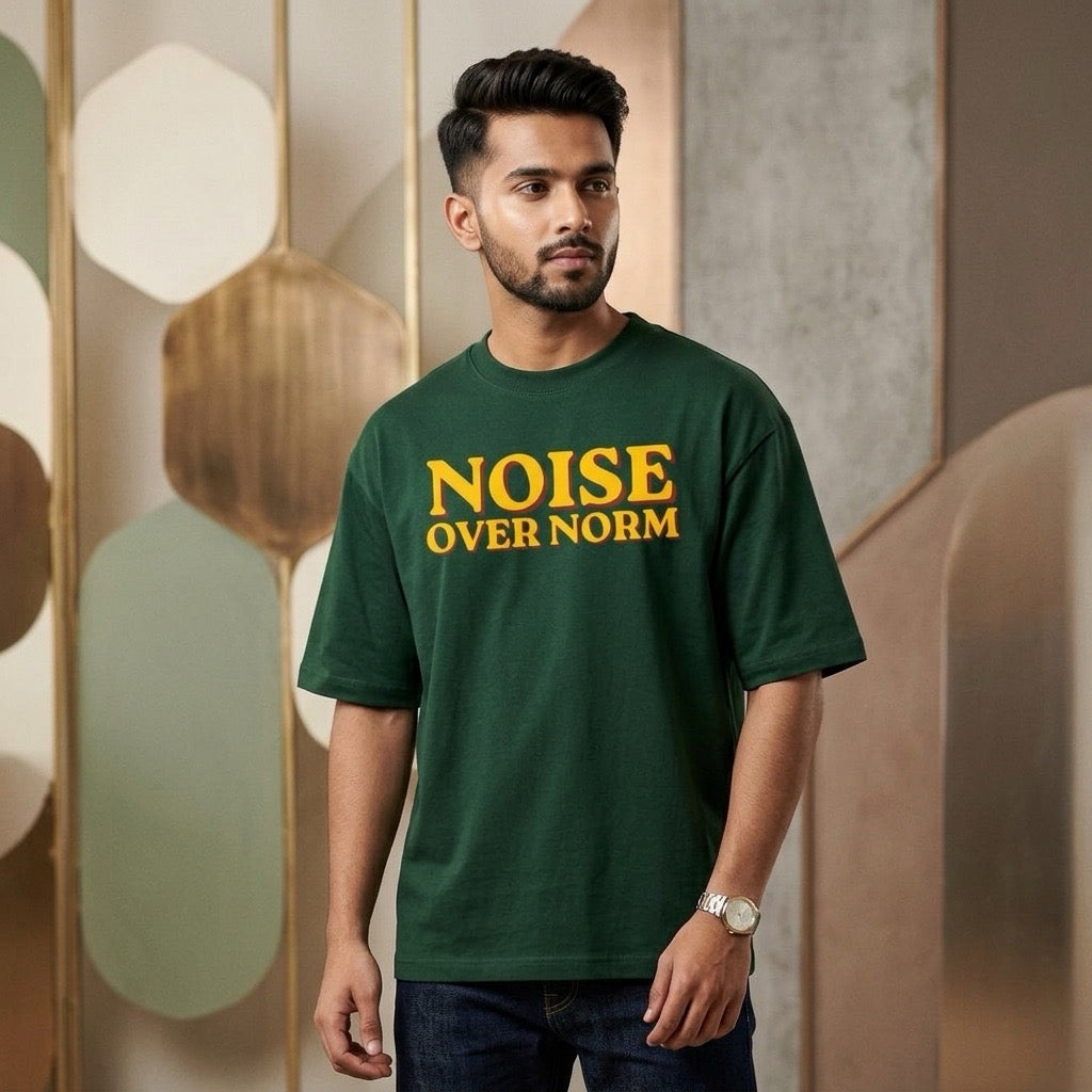 musician wearing a green t-shirt with 'NOISE OVER NORM' text in a stylish interior setting