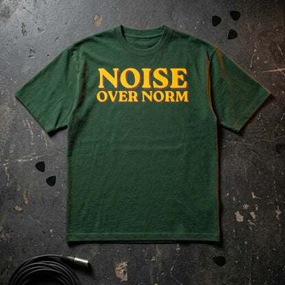 Green t-shirt with 'NOISE OVER NORM' text on a textured dark surface