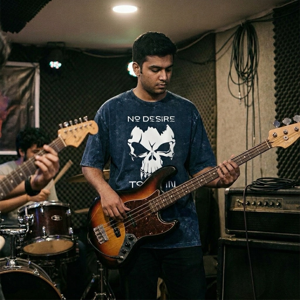 Person playing bass guitar in a music studio with another person playing drums.