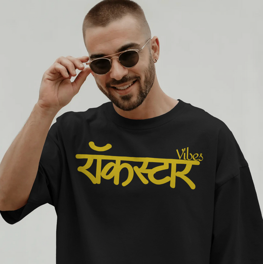 Man wearing a black T-shirt with yellow text of "Rockstar Vibes" on Gold vinyl print and sunglasses, against a plain background - DrummerKong Merch