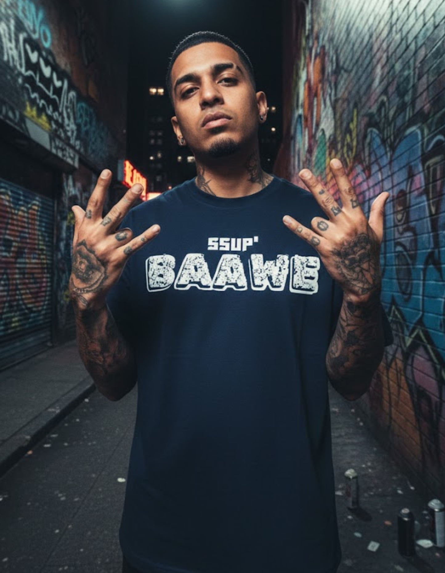 Man wearing a navy blue t-shirt with 'SSUP BAAWE' text in an urban setting with graffiti.