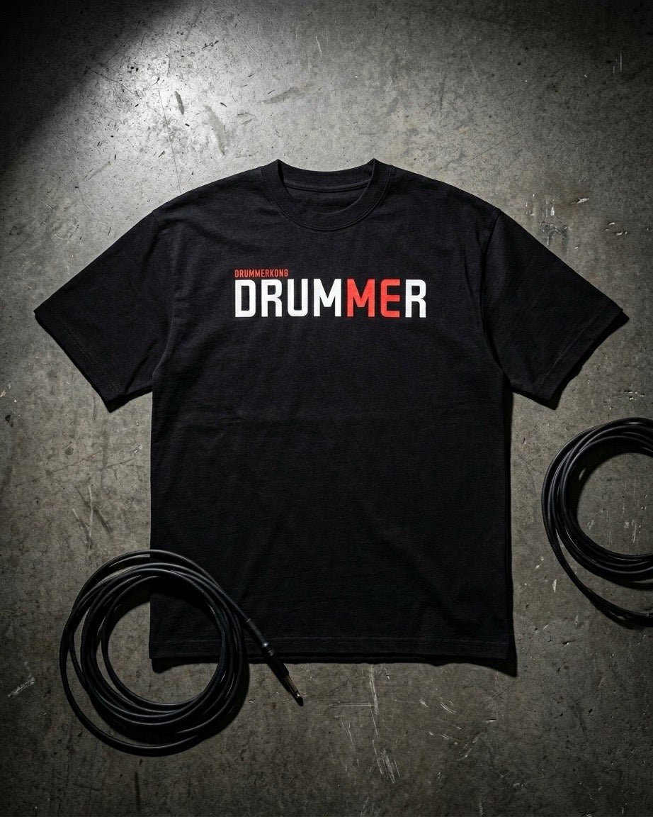 Black t-shirt with 'DRUMMER' text on a textured surface with cables.