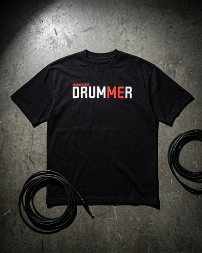 Black t-shirt with 'DRUMMER' text on a textured surface with cables.
