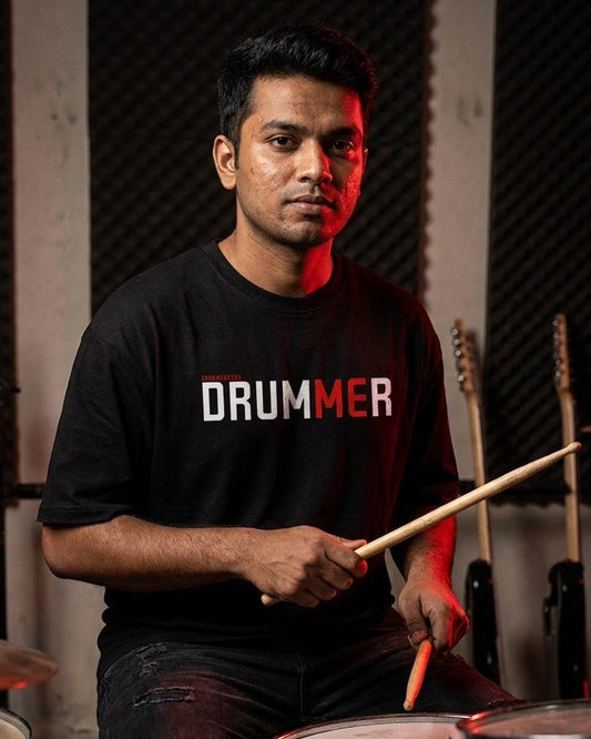 Man playing drums wearing a black t-shirt with 'DRUMMER' text in a studio setting.
