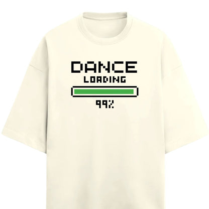 Drummerkong merchandise off-white short-sleeve t-shirt with a pixel-art style graphic on the chest reading 'DANCE LOADING 99%'. The graphic features black text and a green progress bar, set against a plain white background.