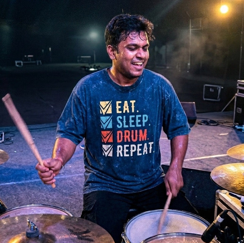 Drummer playing drums on a stage with 'Eat. Sleep. Drum. Repeat.' t-shirt