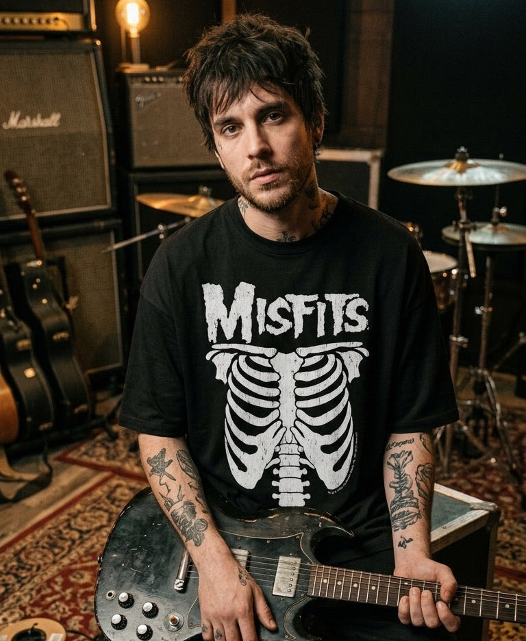Person wearing a Misfits t-shirt holding a guitar in a music studio setting