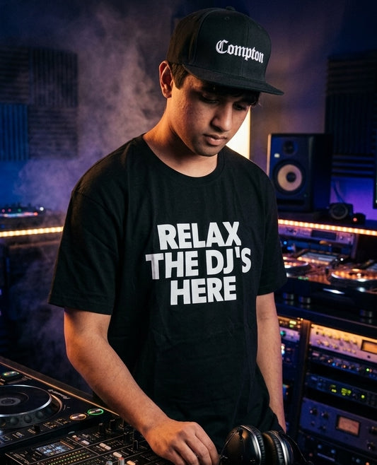 Person wearing a black t-shirt with 'Relax, the DJ's here' text in a music studio setting.